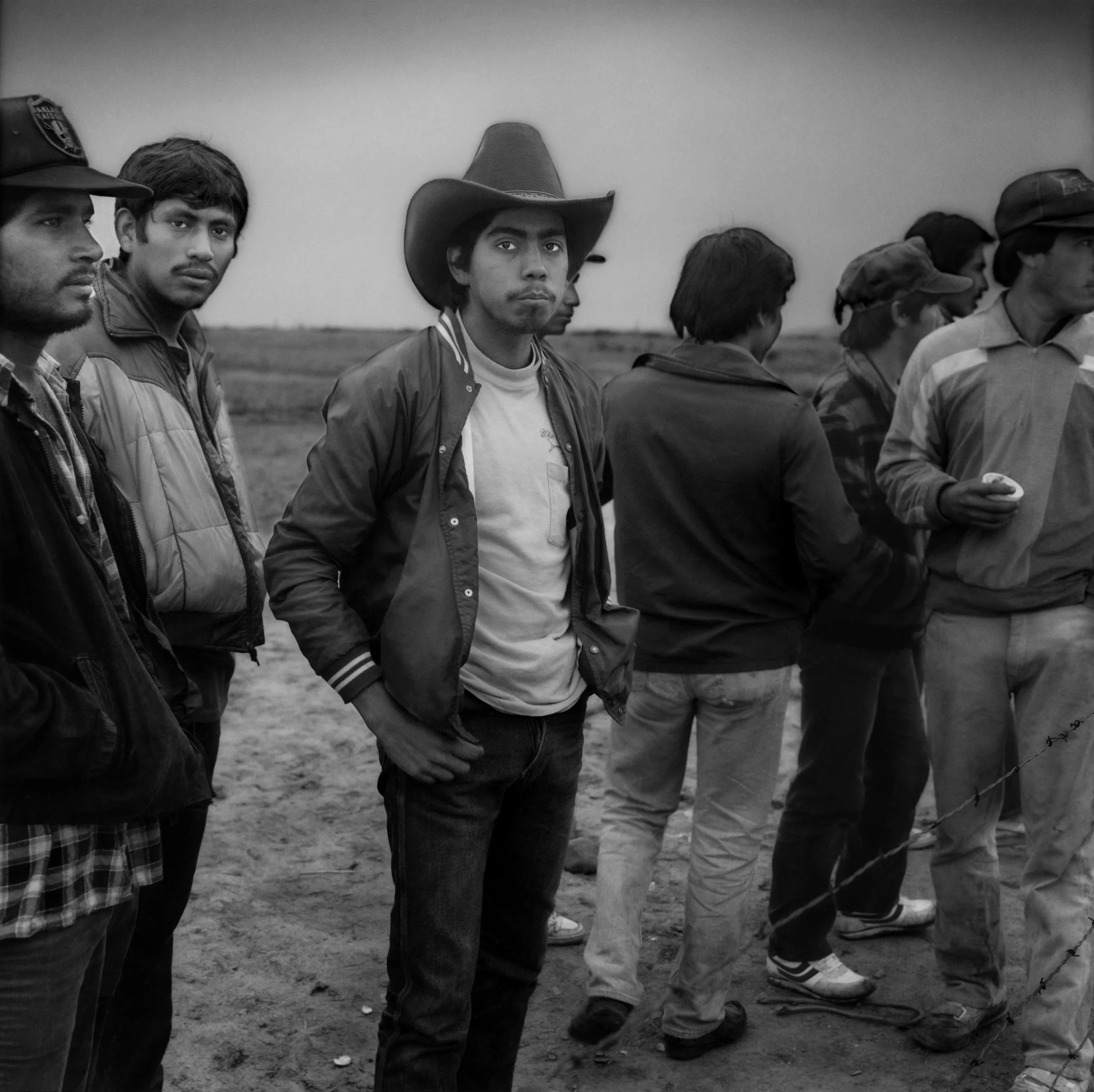 Young undocumented men from Mexico share wary glances in the presence of an American stranger in the fallow fields on the edge of the suburban community of Rancho Rancho Peñasquitos, San Diego, California in 1987. 