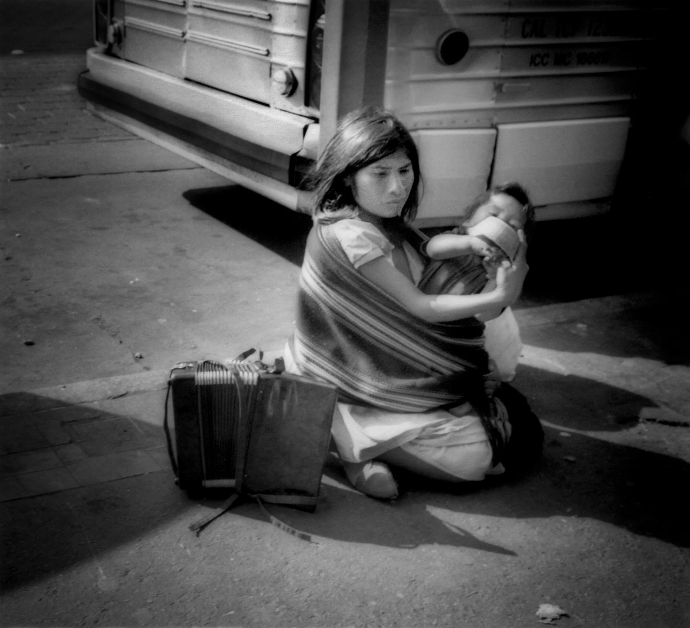 Indigena mother (indigenous probably from Southern Mexico) cradled her infant beside her accordian which sat idle beside her in 2006. She sang Mexican folk songs seated on the pavement of Zona Central to earn money for her family in Tijuana just a few hundred meters from the US - Mexico border. Mexico.