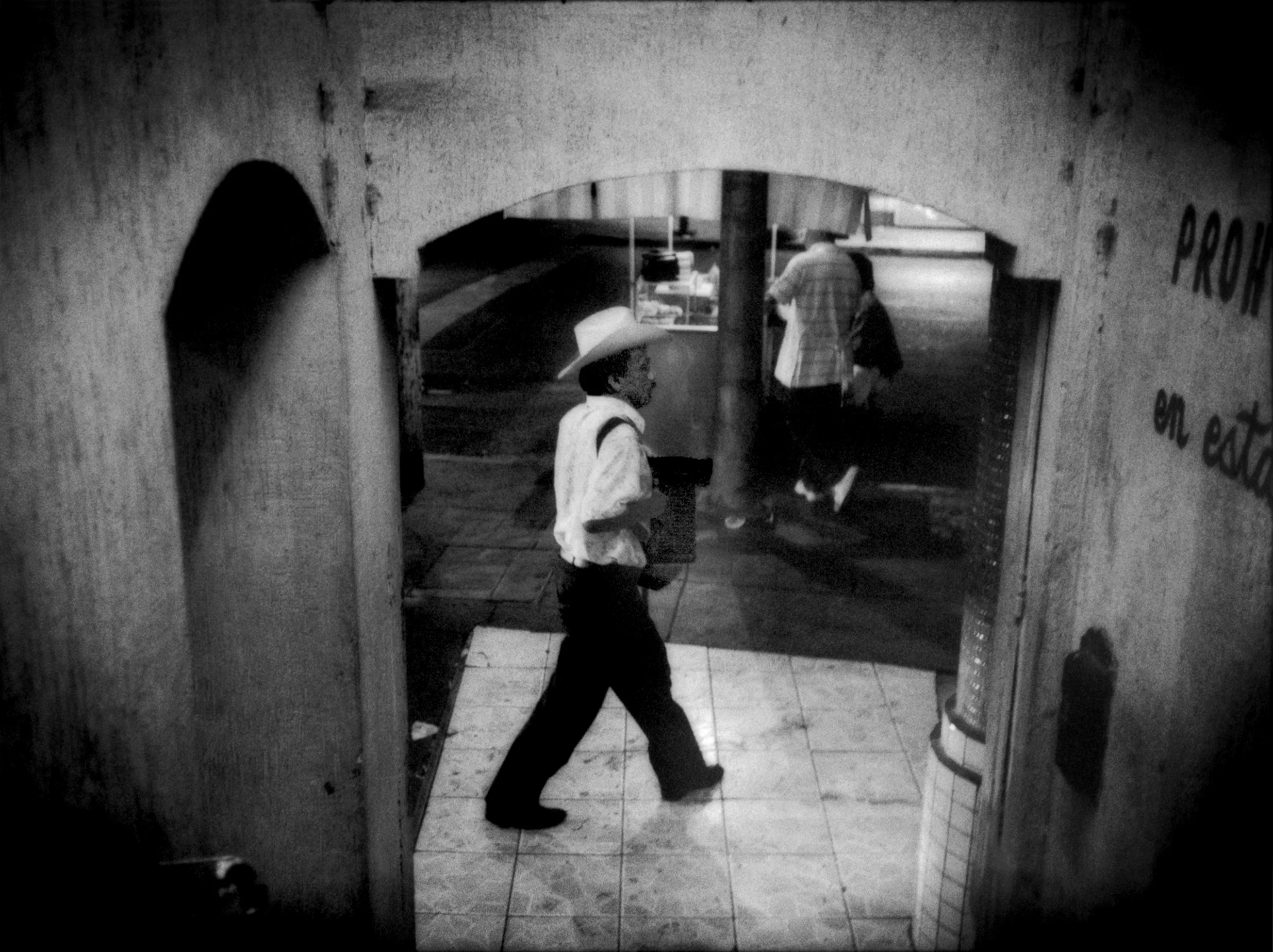Musician carrying his accordion passes door of brothel / hotel entrance in the Coahuila red-light district of Zona Norte, Tijuana, Mexico. 2007