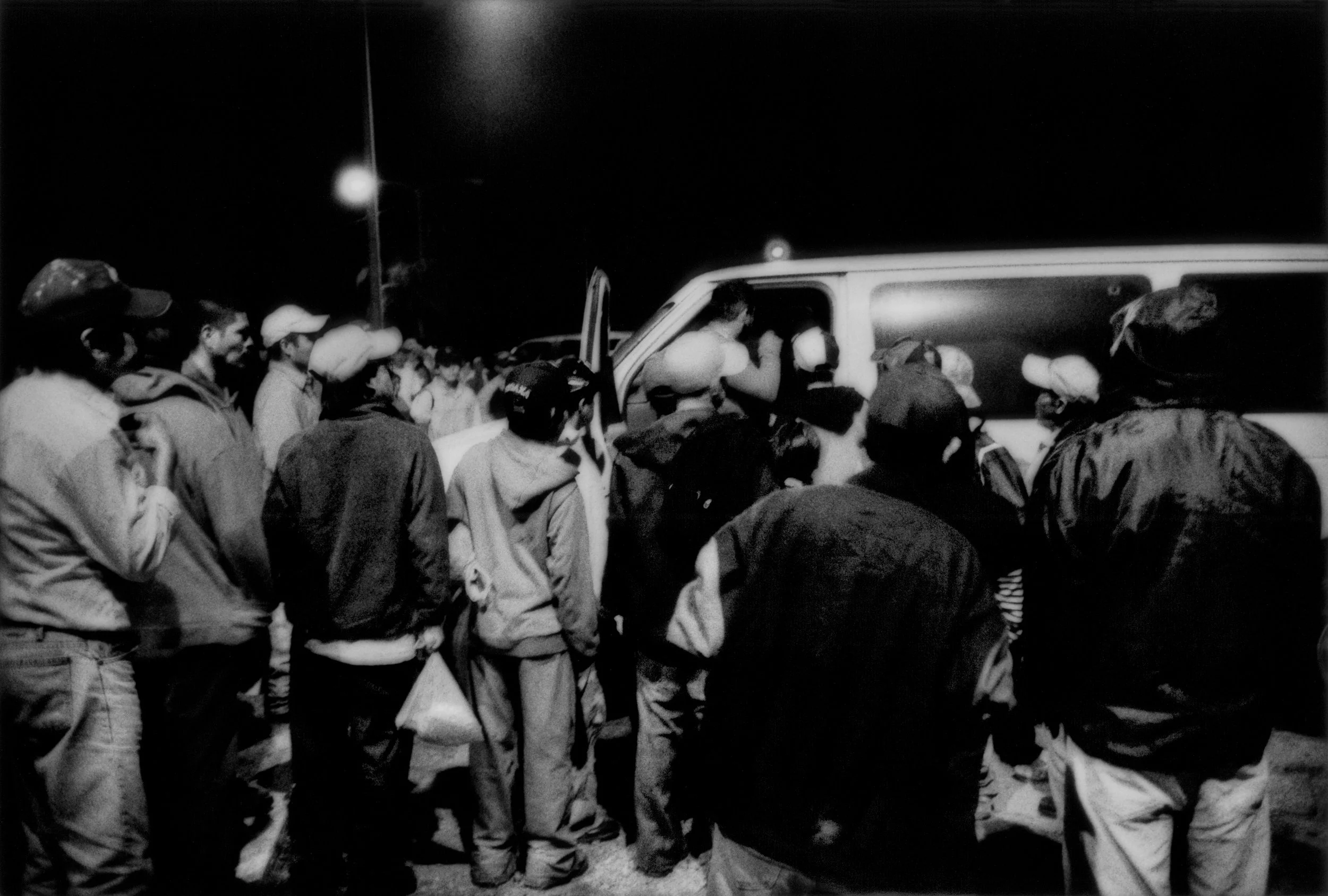 Migrant workers, mostly Mexican, Central American and Haitians, anxiously crowd van of a crew boss offering precious day labor in a year where the winter tomato crop has been decimated by a prolonged freeze. Immokalee, Florida. 2010