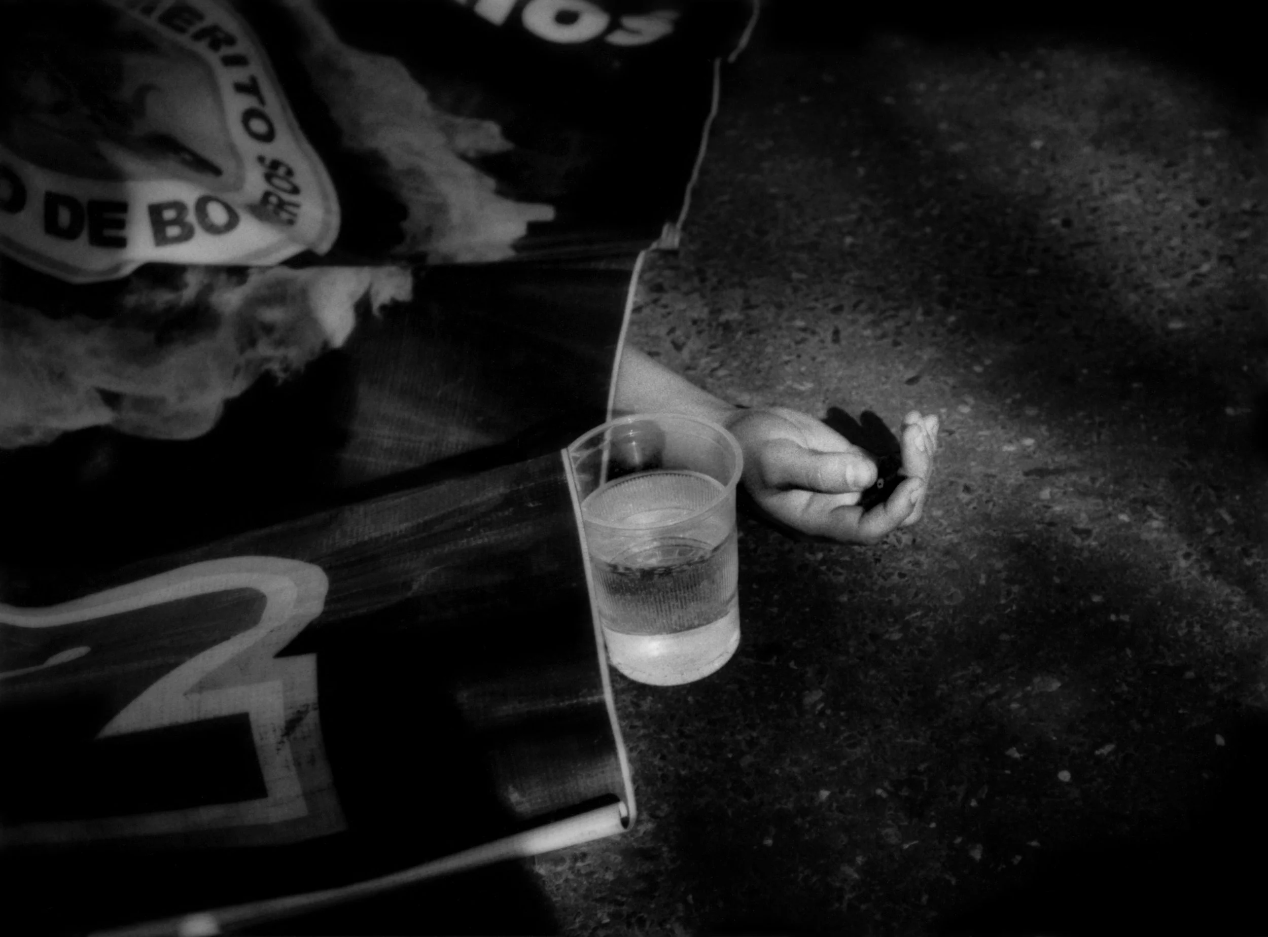 A glass of water has been set on the pavement beside the body of a 23 year old motorcyclist who, police alleged, was killed after he and a pistol-wielding accomplice robbed a car on a Guatemala City highway in broad daylight. During their attempted escape, witnesses said, another driver, watching this very common robbery unfold, sideswiped the motorcycle sending the driver and his accomplice to the pavement, killing the driver. The injured accomplice escaped on foot into this crime-ridden Zone 7 neighborhood. Guatemala City, Guatemala. 2014
