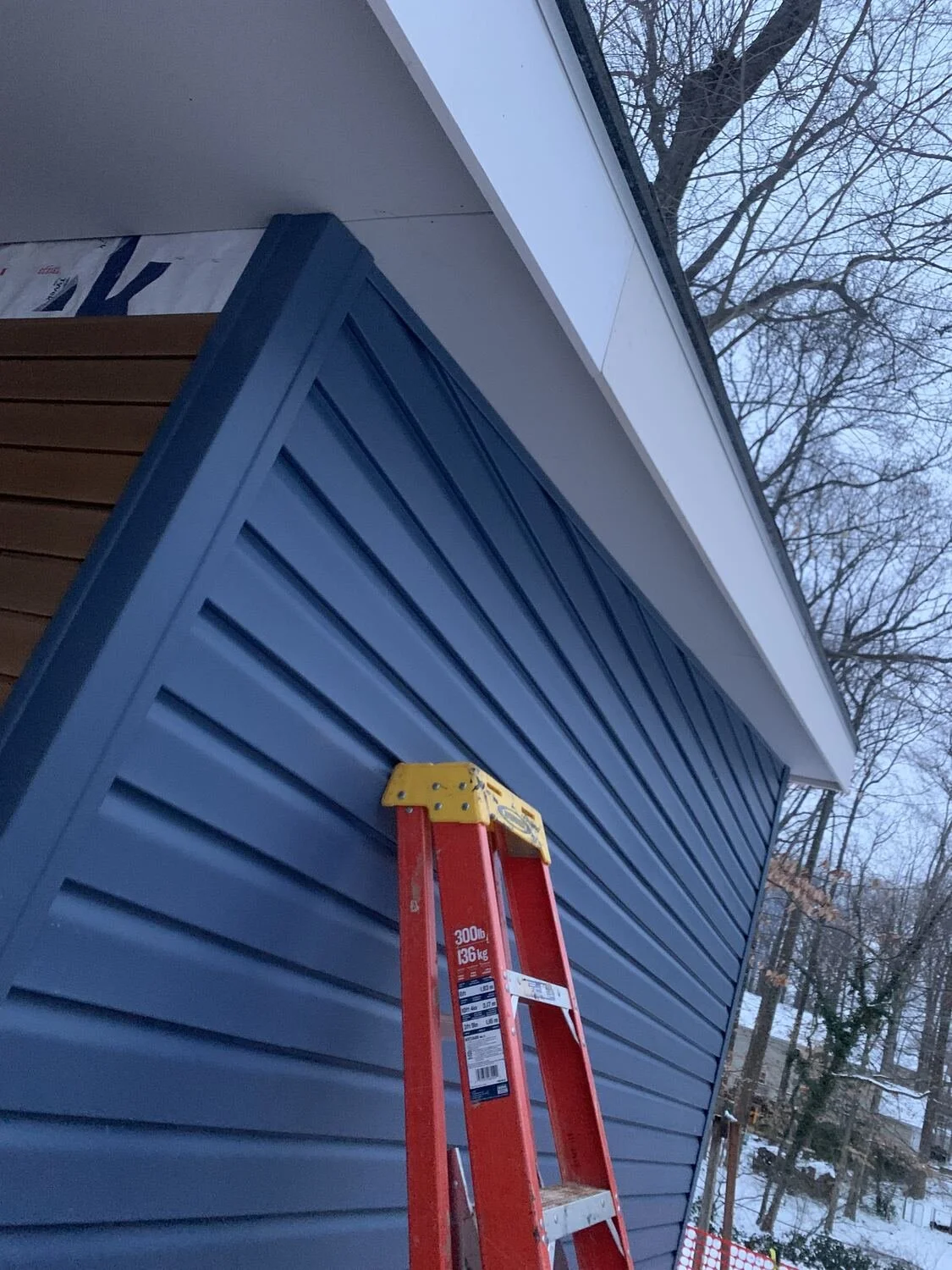 Installing matching blue siding on the Annandale workshop addition
