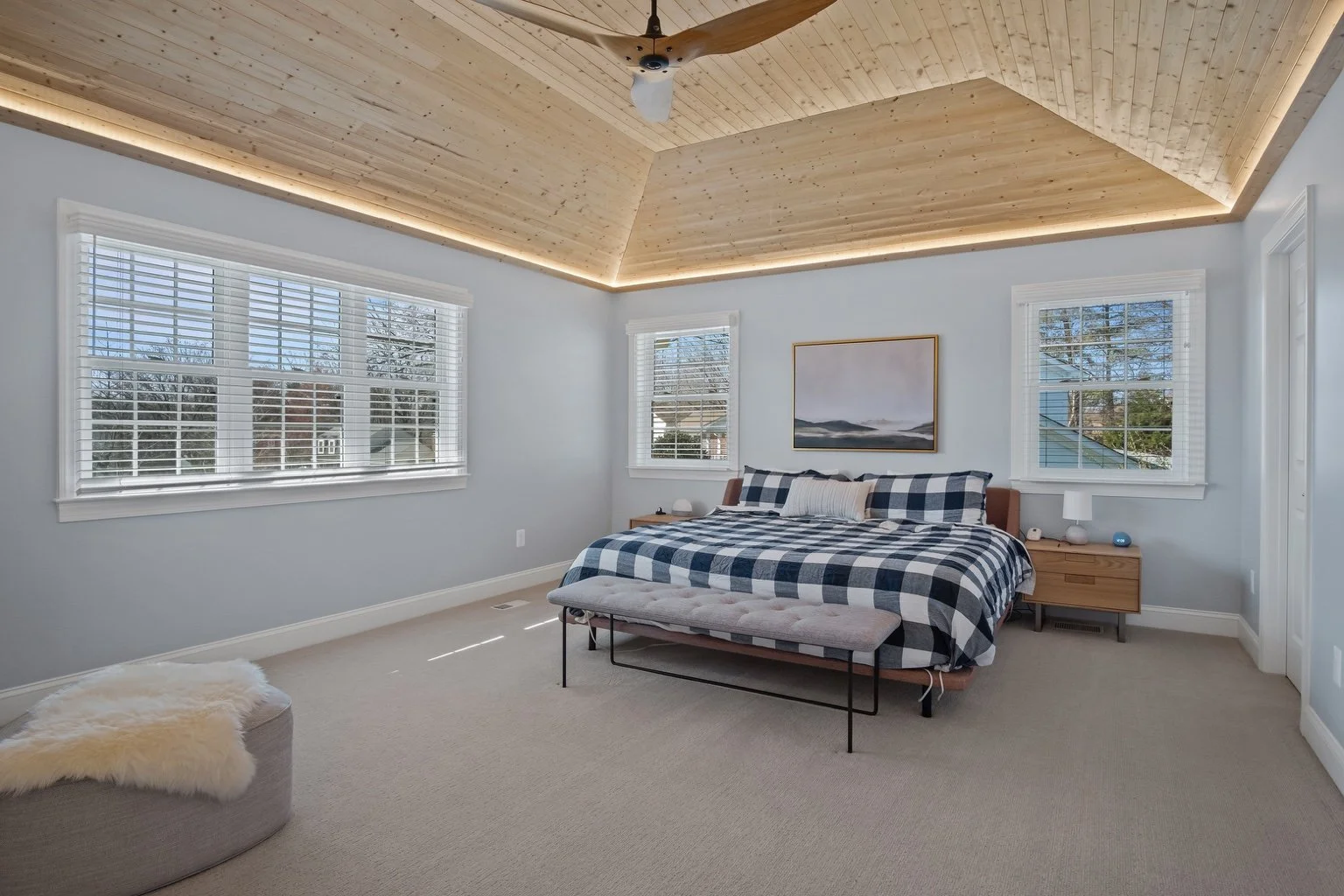 Finished primary bedroom above a Vienna garage with a vaulted pine ceiling, ceiling fan and windows.