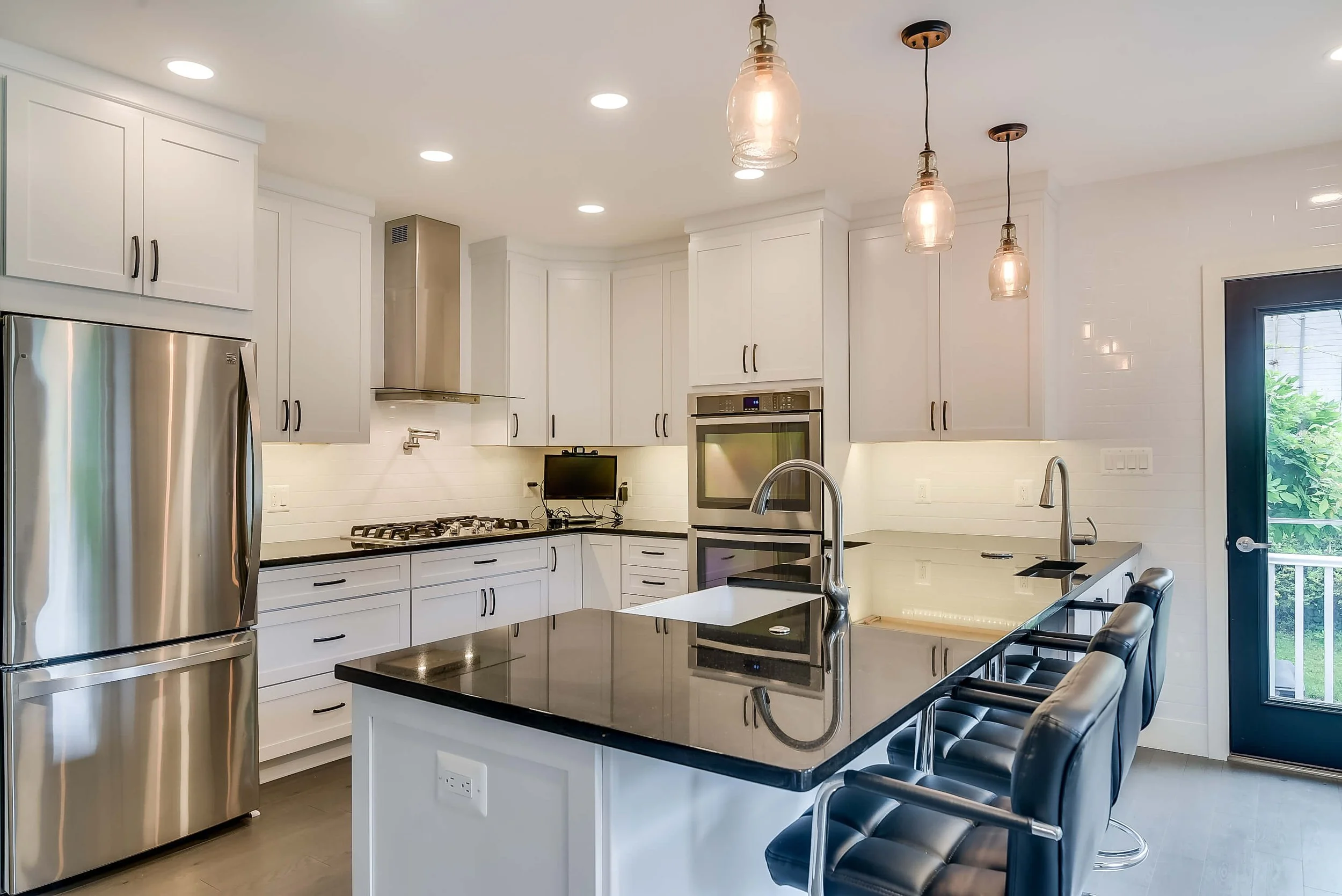 Kitchen with white cabinets black countertops and island seating.jpeg