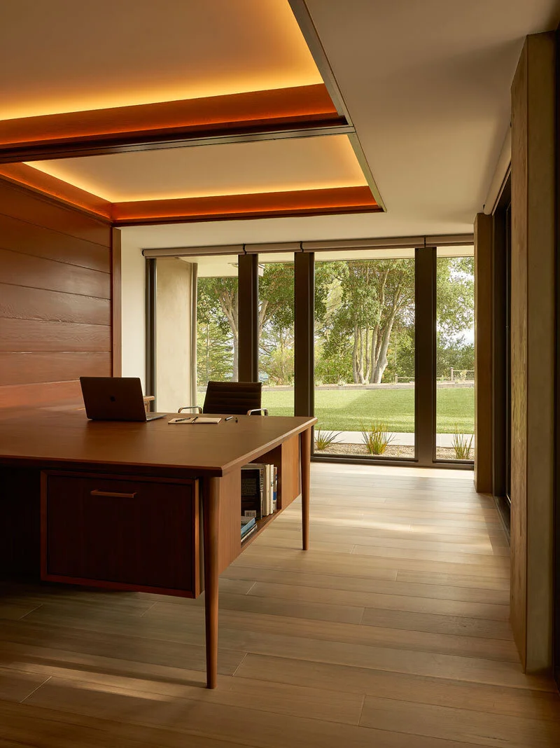 Home office with custom-made walnut desk with wooden floors and Fleetwood doors overlooking the backyard in mid-century-modern home in Lafayette California
