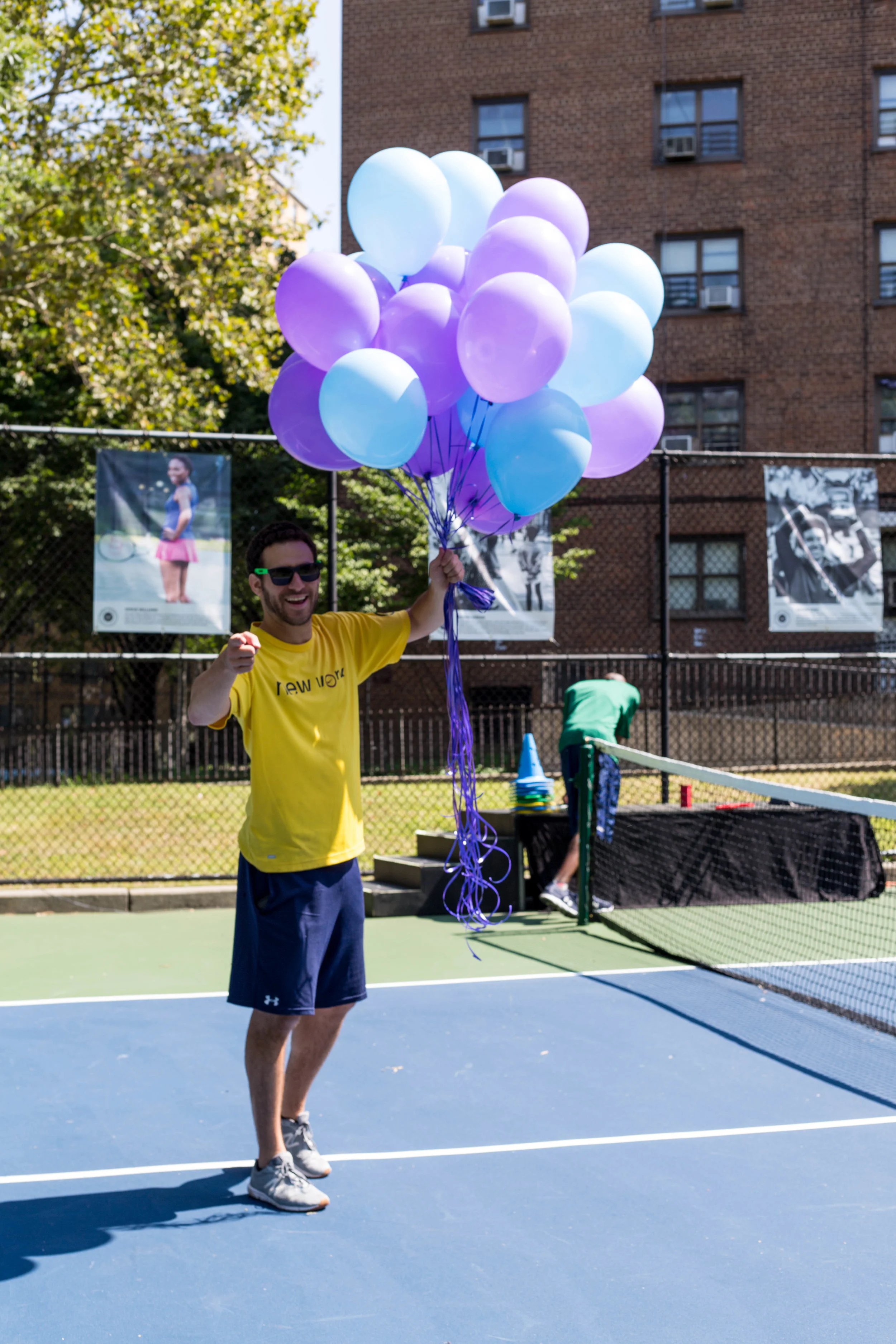 Volunteer Chase Atneu sets up for the community ribbon cutting at the Sumner Housing Project Tennis Court.