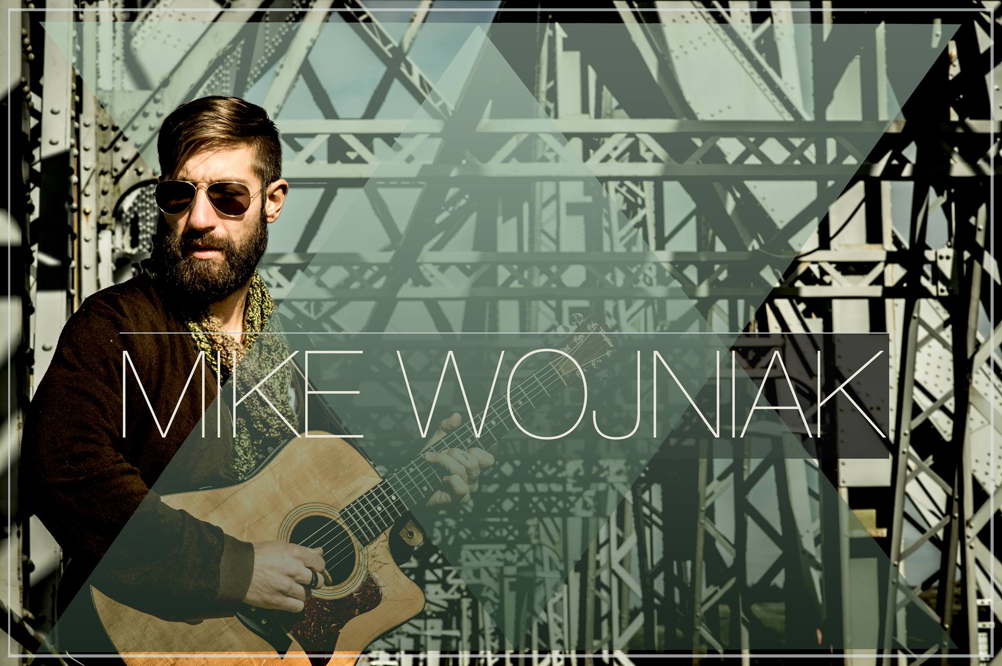 Mike Wojniak with his guitar on a bridge.