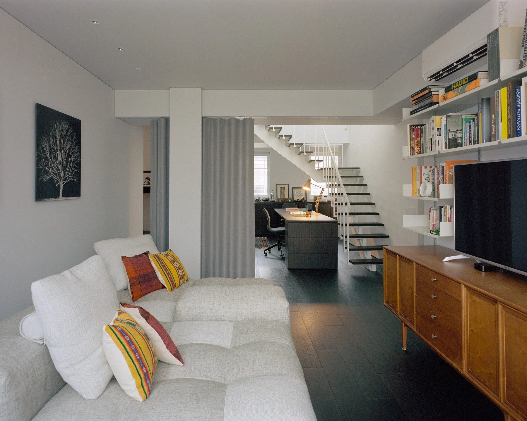 | 享受開放格局的同時，如何減緩夏季冷氣費？

無隔間的客餐廳設計，讓家裡看起來明亮又開闊。但到了夏天，大空間往往會讓冷氣變得耗電。如何在「空間寬敞」和「省電」之間取得平衡？其實，加一道窗簾就能解決。

．拉上窗簾，冷氣不外流
在大尺度的開放空間中（例如本案客廳與工作區的交界、樓梯與餐廚之間），只在其中一區活動時，拉上這道落地簾，就能把空間暫時分成兩個獨立的冷房。冷氣不外洩，降溫更快，自然也就更省電。

．預留收納，軌道隱形，維持極簡開闊 
為了不破壞天花板的平整，在平面配置之初，便在天花板上預