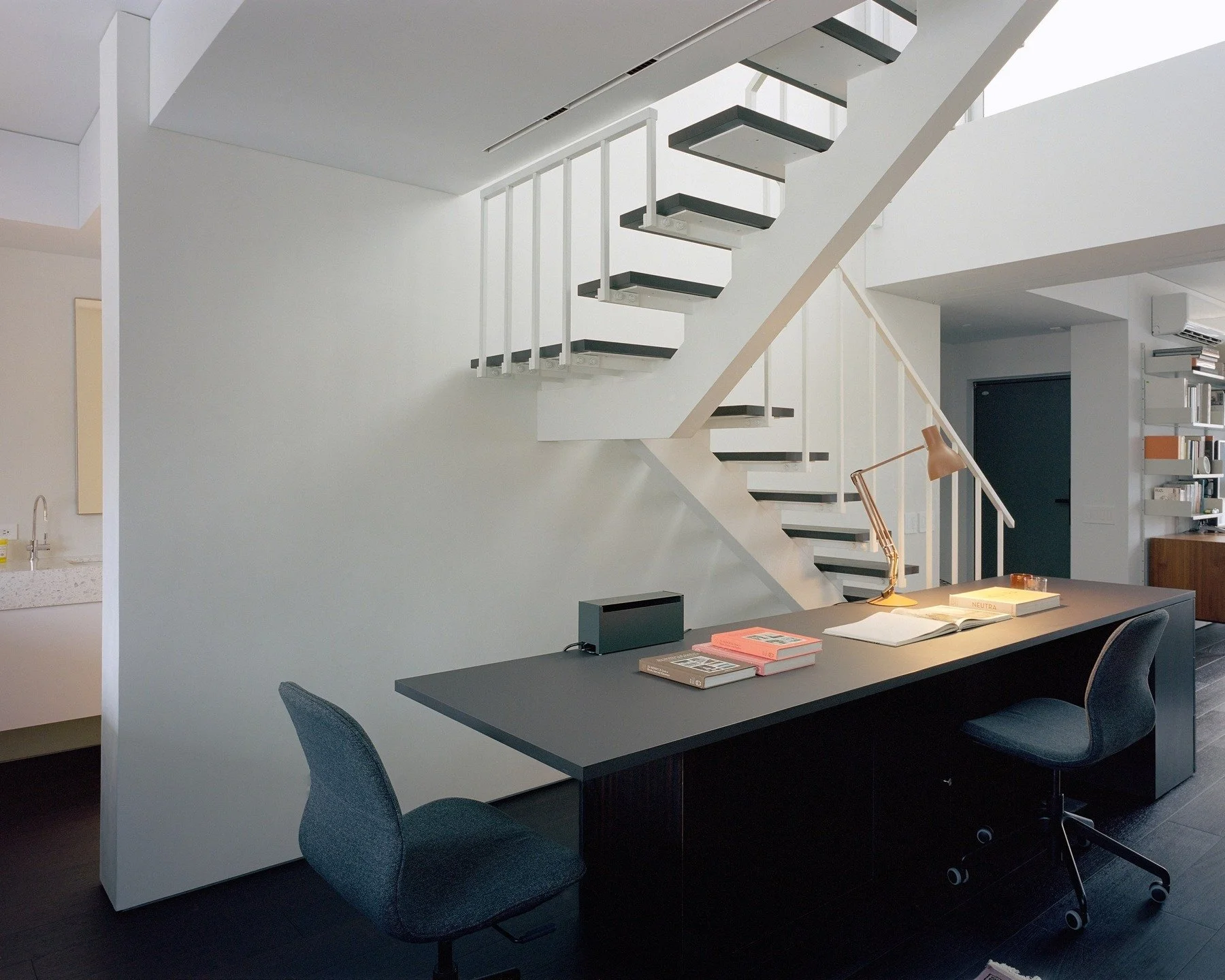 | Stairs are not merely a means of vertical circulation; they are also key to bringing natural light into older homes.

Architects often design staircases as sculptural elements within a space. Even though a staircase is a highly functional component (providing vertical circulation), it can easily be highlighted as a design focal point, serving as a visual anchor between floors or even functioning as a standalone sculpture. Additionally, given the limited natural light in older homes, staircase design must be approached with care to avoid having bulky structures block the path of light.

This project ultimately adopted a single-stringer structure. Compared to the traditional double-stringer design, the single-stringer significantly simplifies the framework, creating a lighter visual effect. Combined with open treads, light can directly penetrate the gaps between the steps, flowing from the floor-to-ceiling windows above into the lower-level interior. This alleviates the traditional sense of darkness and oppression, representing the most practical solution in the design.