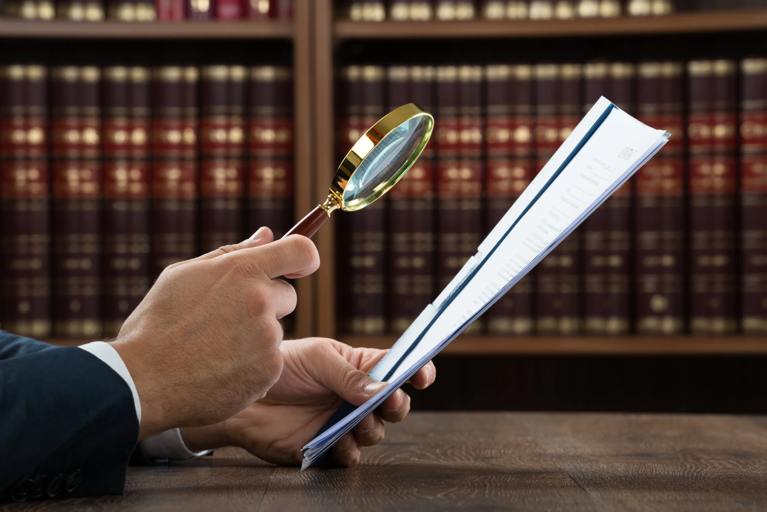 LawyerExaminingDocumentsWithMagnifyingGlass.jpeg
