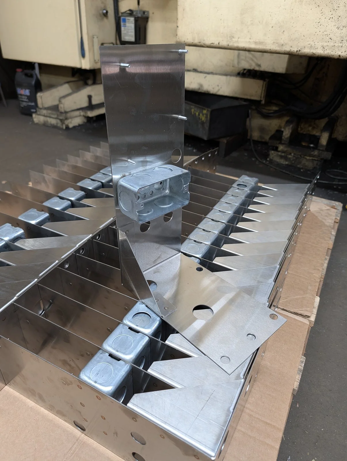 Formed stainless steel mounting plates with electrical boxes attached, packed on a pallet
