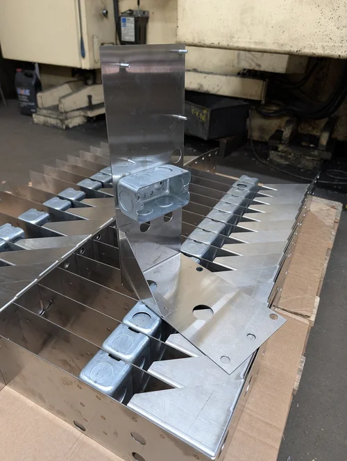 Formed stainless steel mounting plates with electrical boxes attached, packed on a pallet