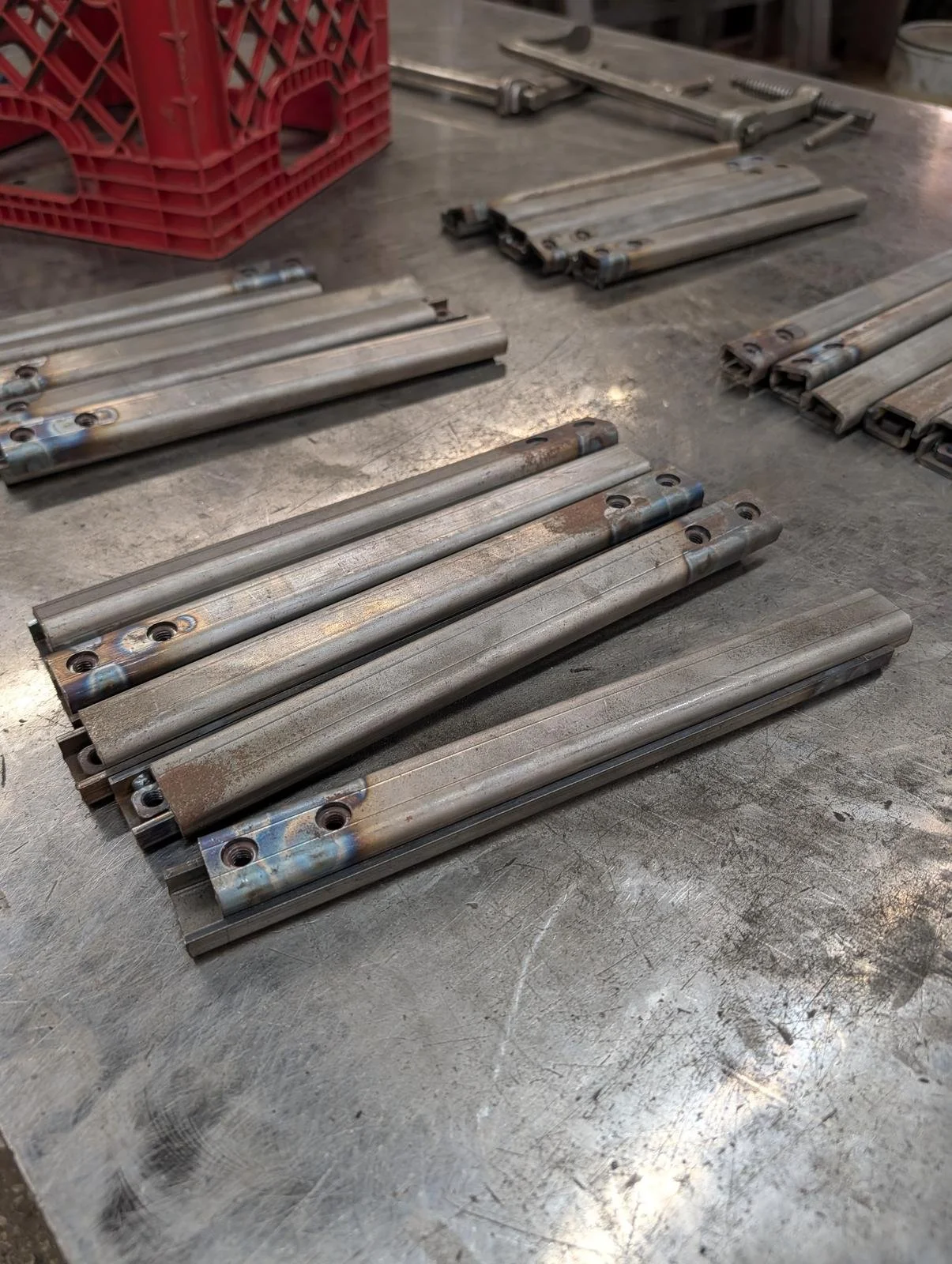 Welded steel tube rails with mounting tabs laid out on a workbench