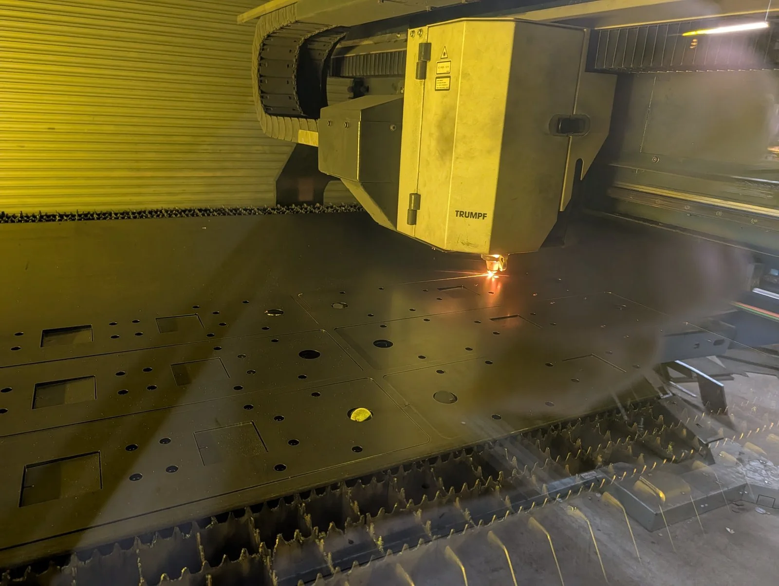 Fiber laser cutting head cutting holes and cutouts in a steel sheet