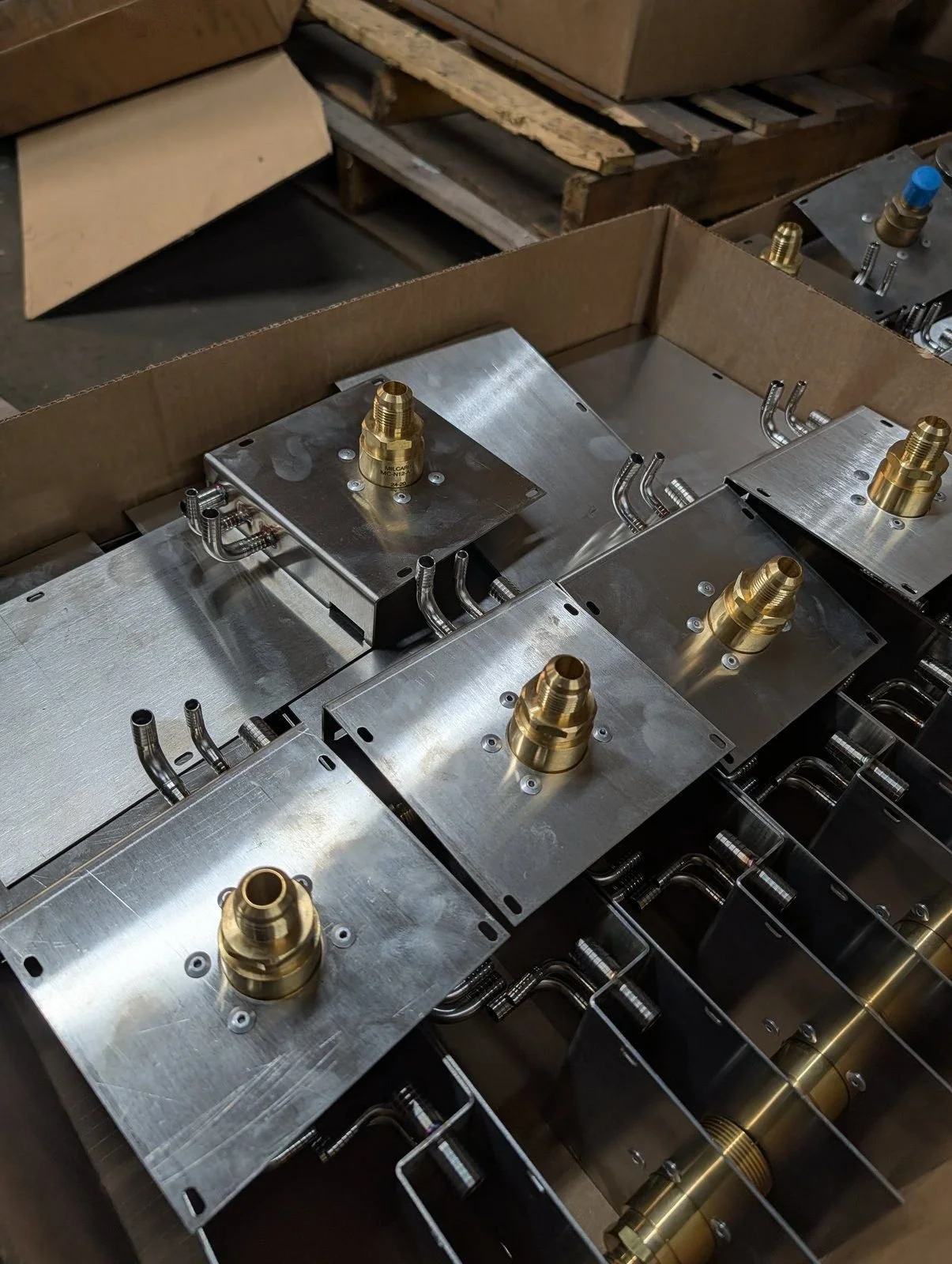 Stainless steel brackets assembled with brass fittings and bent tube stubs, packed in a box
