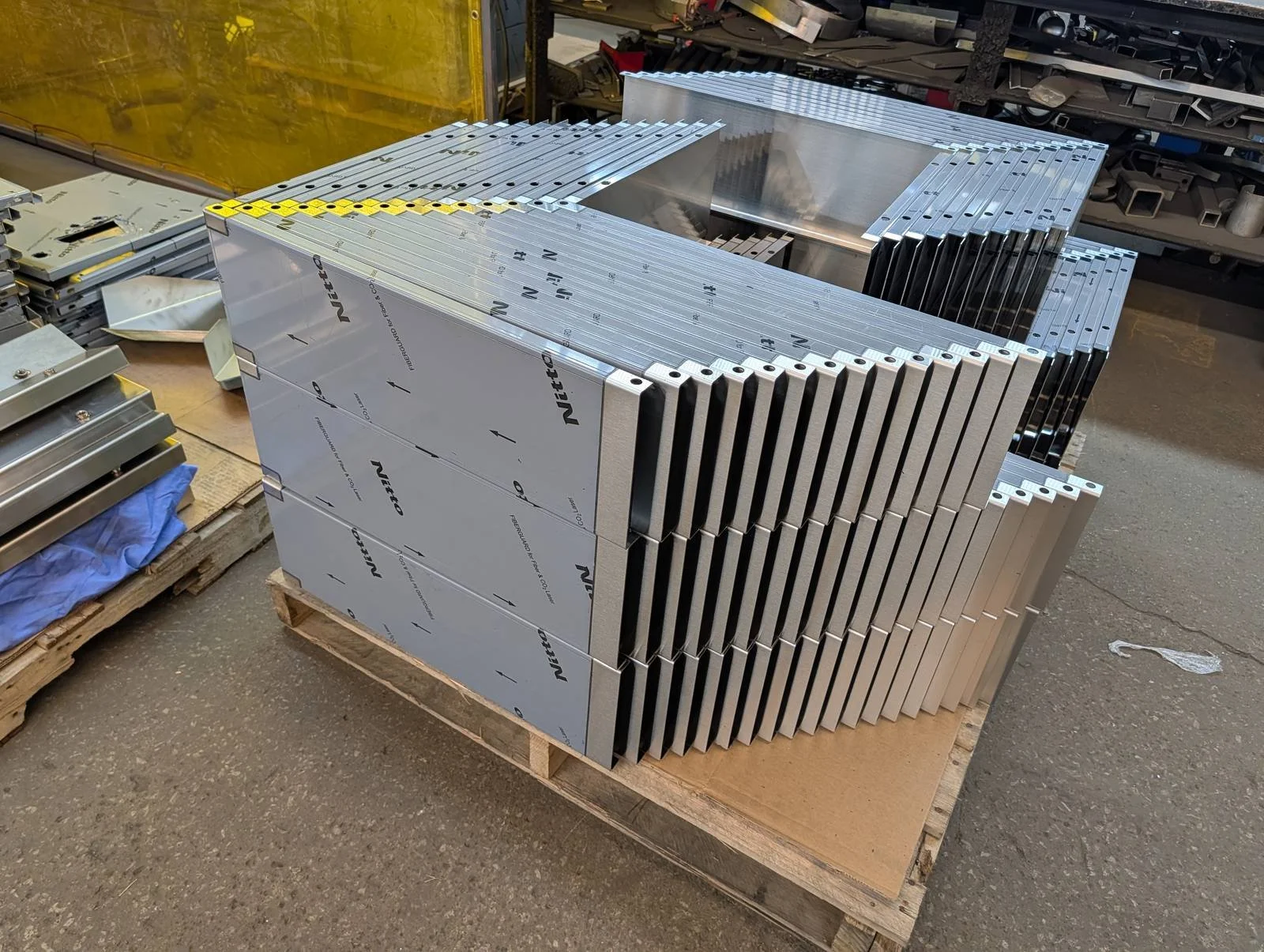 Stack of formed stainless enclosure panels with protective film on a pallet