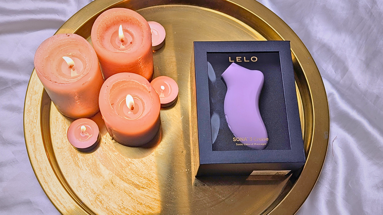LELO SONA 3 Cruise in packaging next to candles
