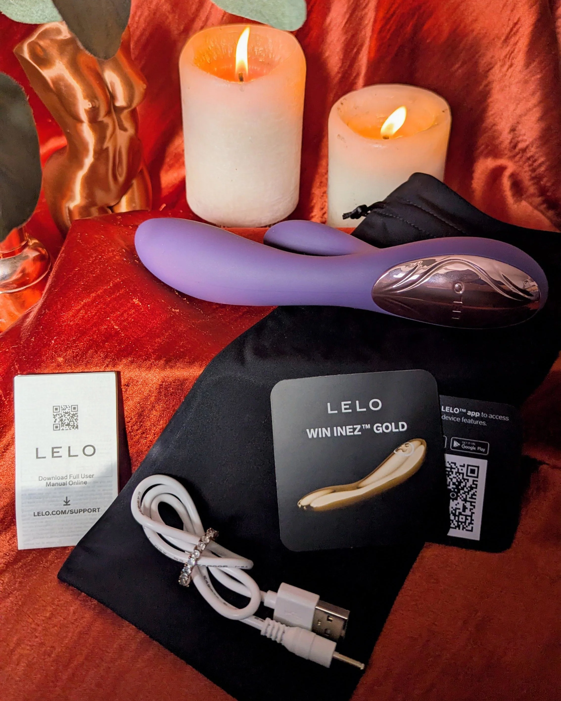 Purple LELO Ina Thrust thrusting rabbit vibrator alongside accessories, including USB charging cable, storage bag, instruction manual and warranty card
