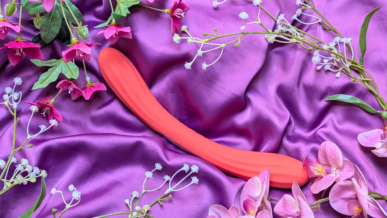 LELO Boomerang double ended vibrator in coral red surrounded by flowers