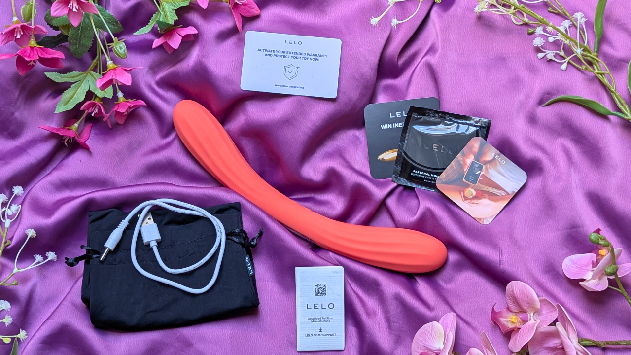 LELO Boomerang double ended vibrator in coral red with  charging cable, instruction manual, warranty card, storage bag and LELO personal moisturiser