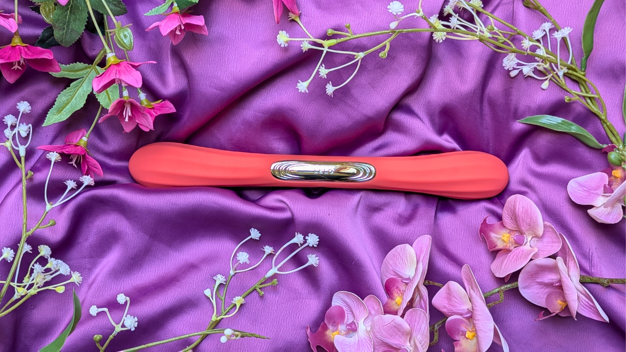 LELO Boomerang double ended vibrator in coral red surrounded by flowers