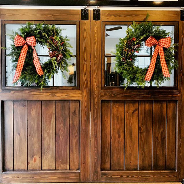 Beautiful split sliding doors between a kitchen and living room. The Christmas wreaths add a perfect seasonal touch! #barndoors #slidingbarndoors #farmhouse #farmhousestyle #farmhousedecor #farmhousechristmasdecor #barndepot #handcrafted #lancasterma