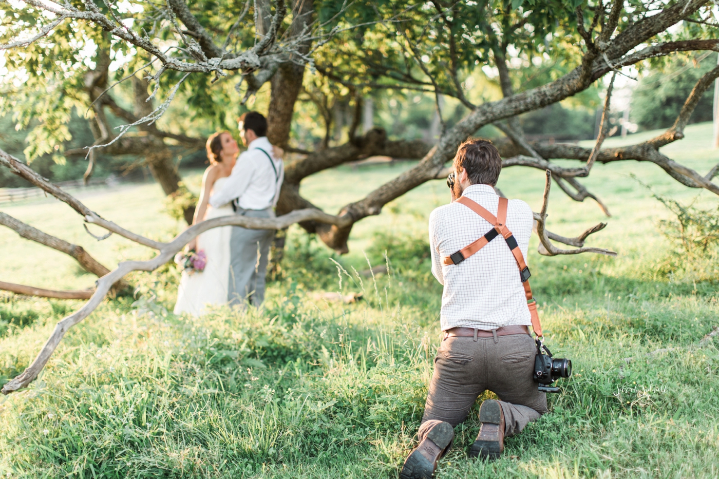 A man kneels down to get a good shot of a bridal couple.