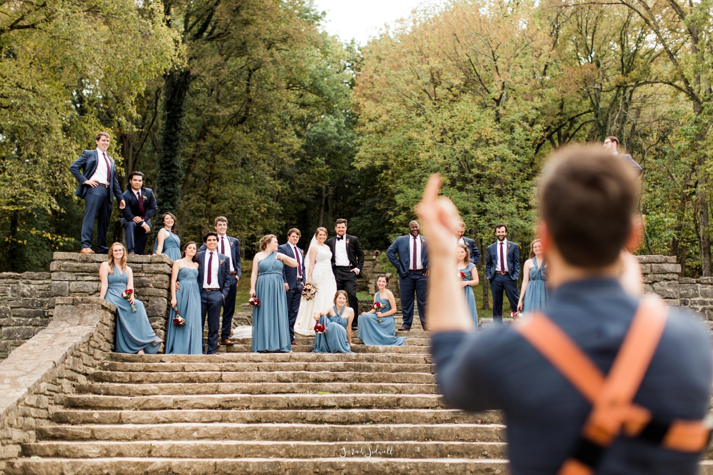 A photographer directs a wedding party to stand closer.