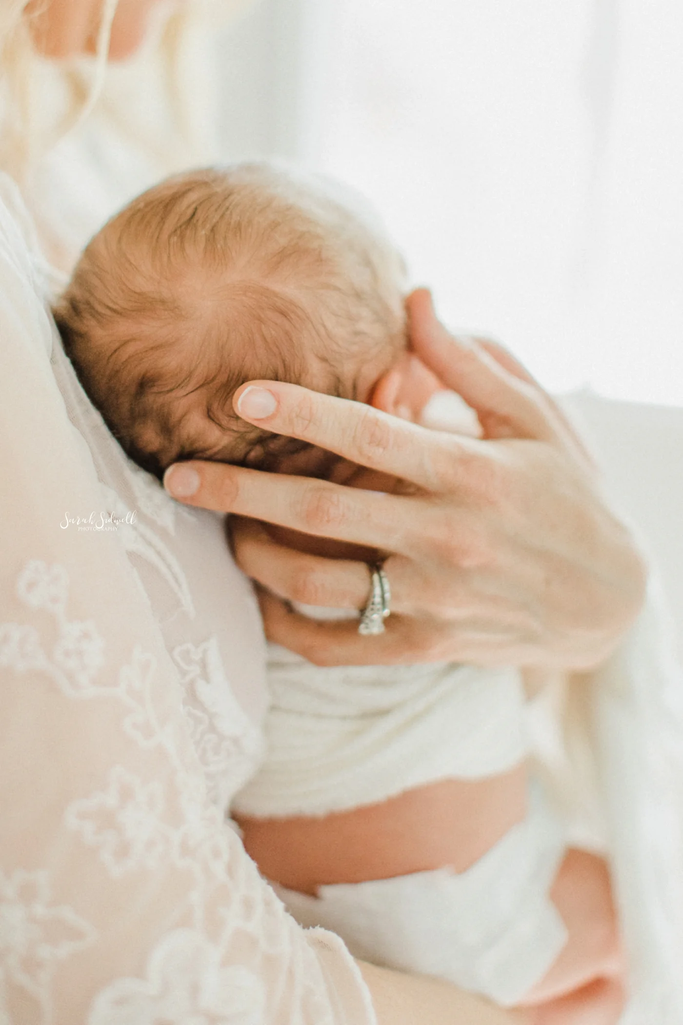 A newborn is held in the hands of his mother.