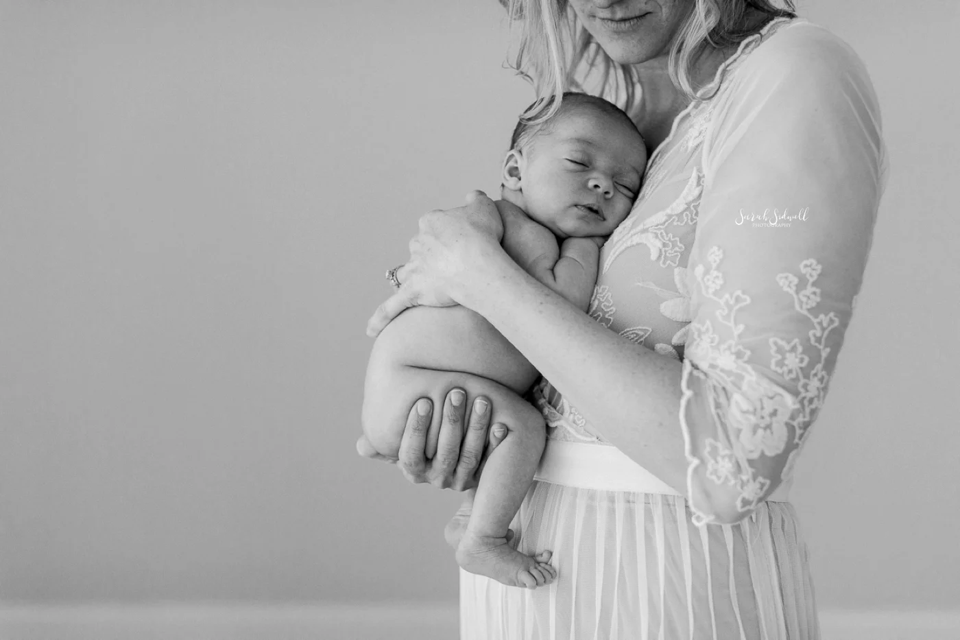 A mother gently cradles her newborn close to her.
