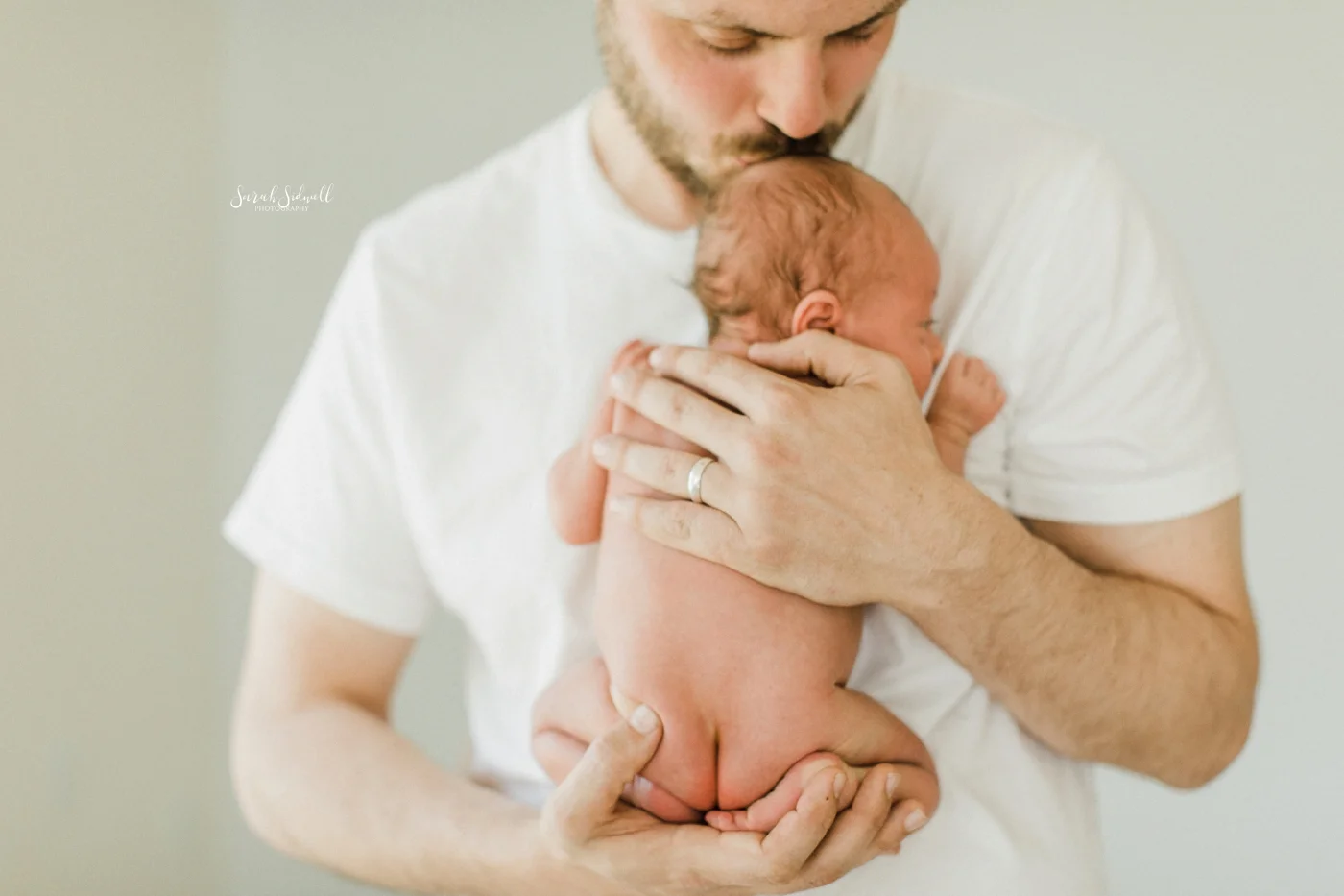 A new father holds his newborn close to his chest.
