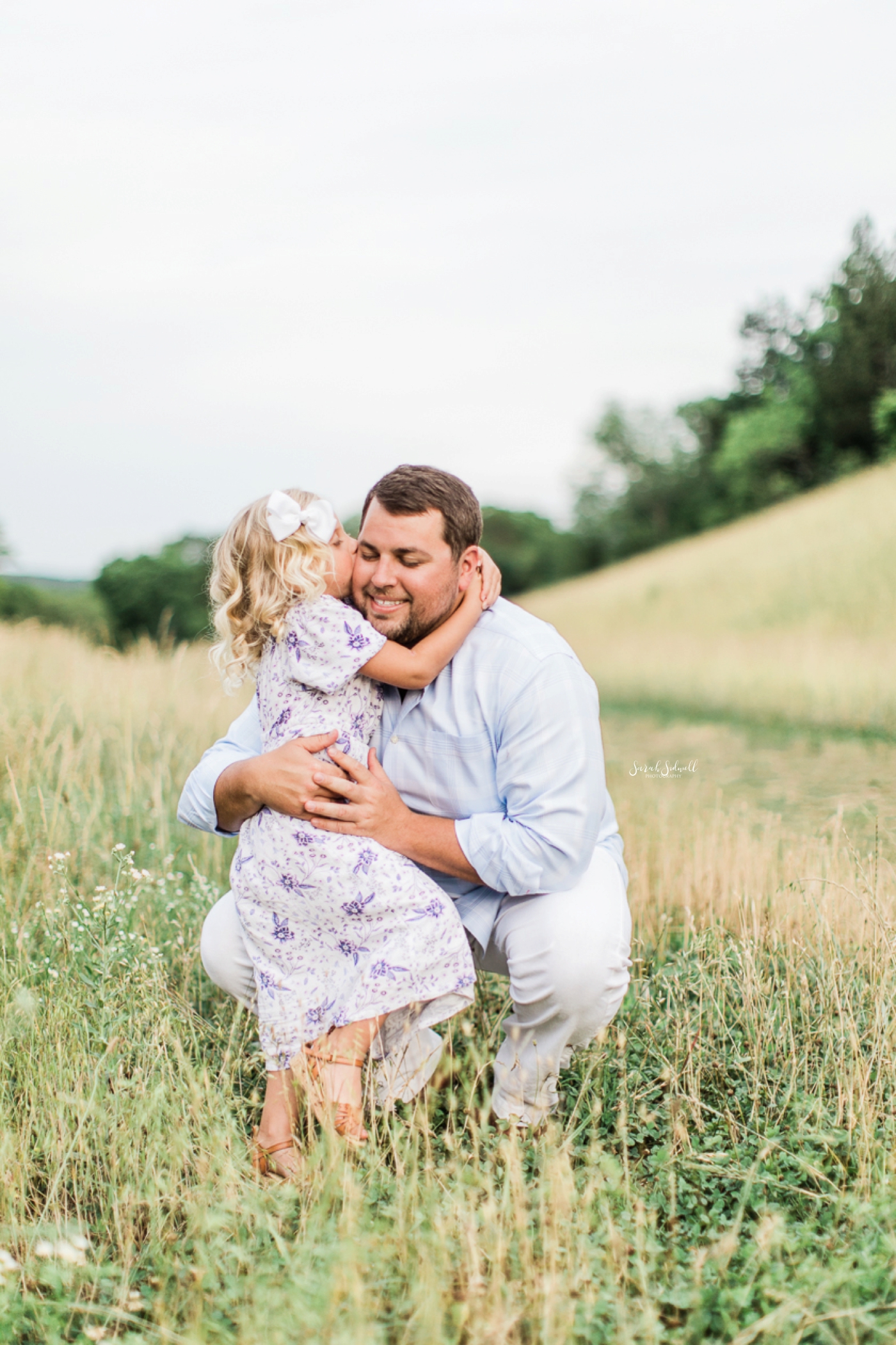 A girl hugs her dad around her neck.