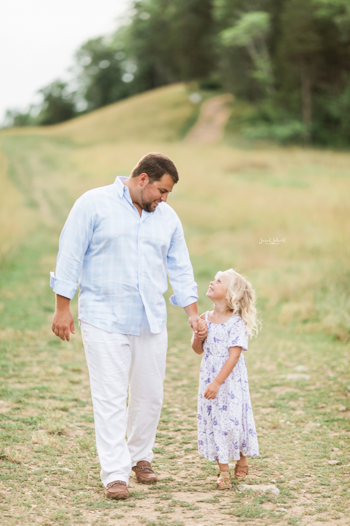 A dad walks with his young daughter.