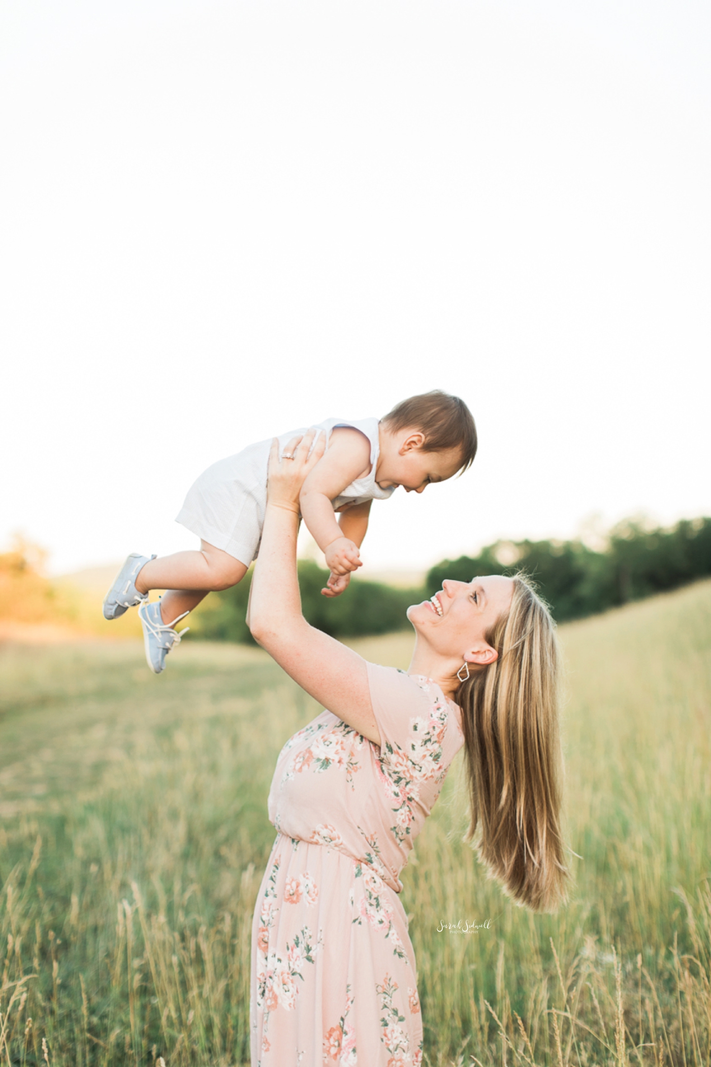 A woman holds her baby up in the air to play.