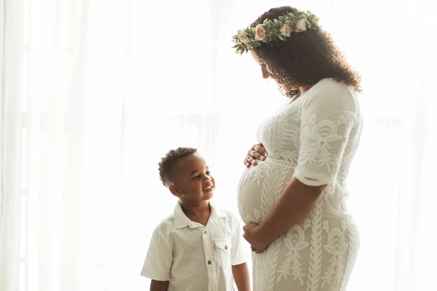 A young boy looks at his mom's pregnant belly.