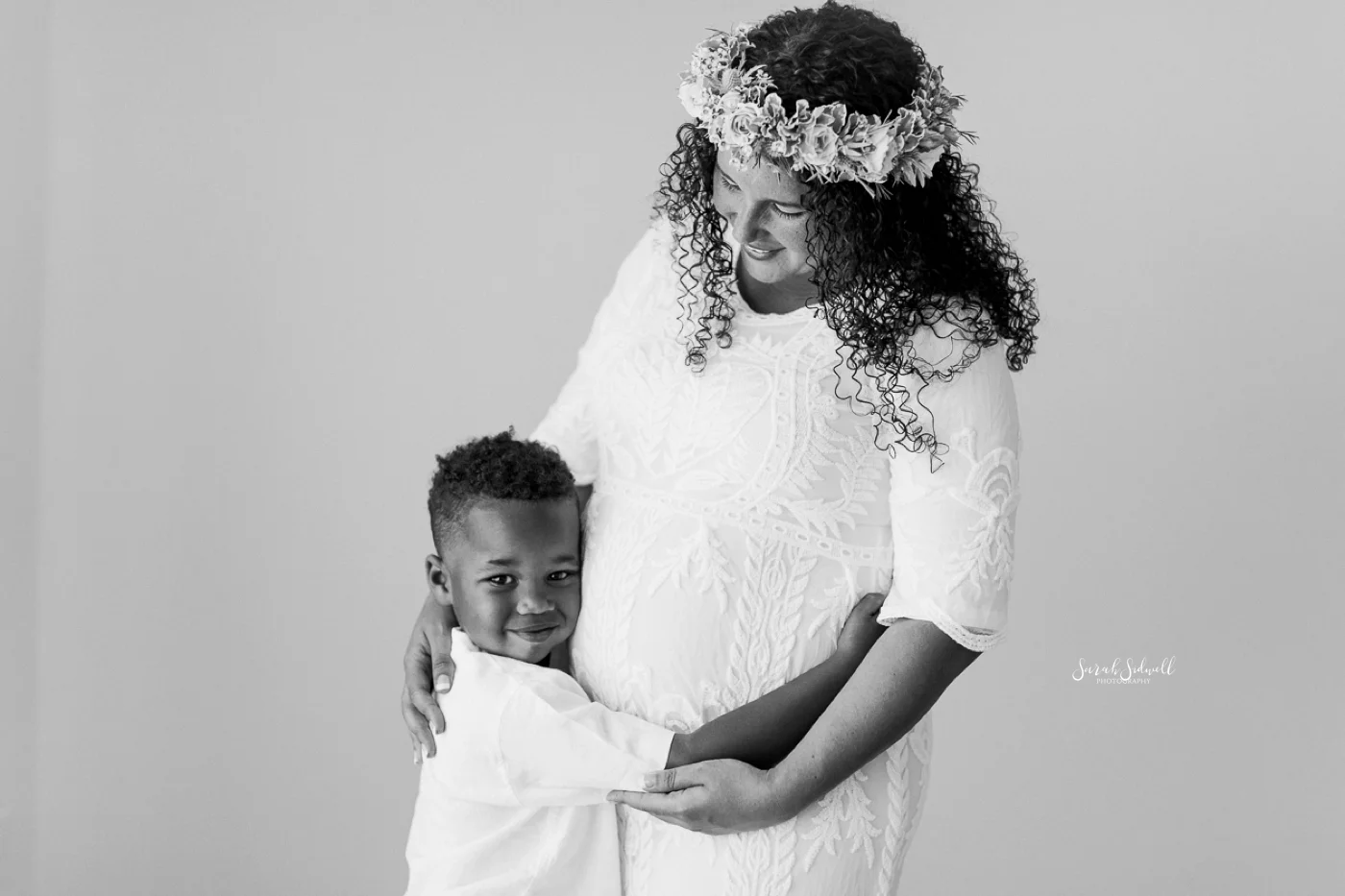 During a family maternity session, a boy hugs his mom.