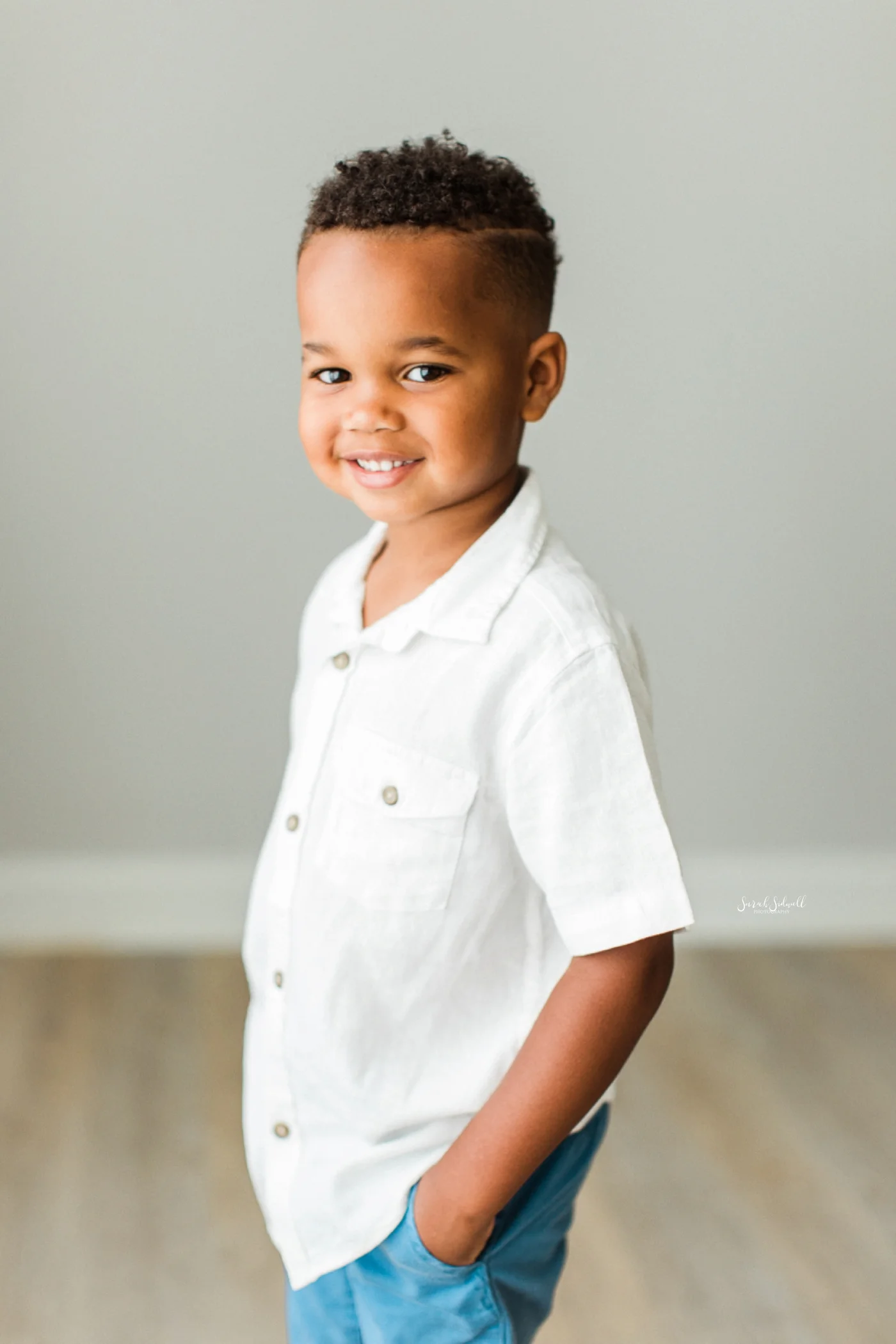 A young boy stands with his hands in his pockets.
