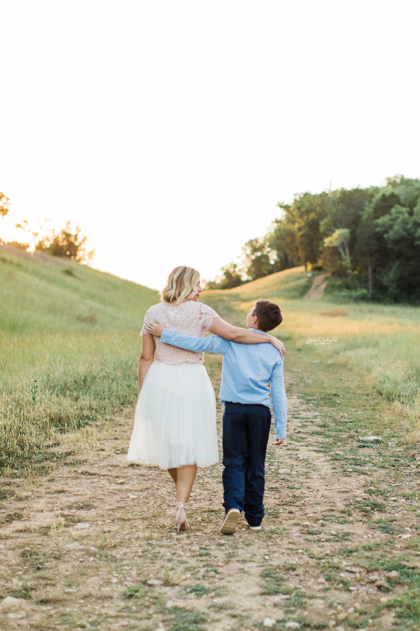 A mom walks down a path with her son.