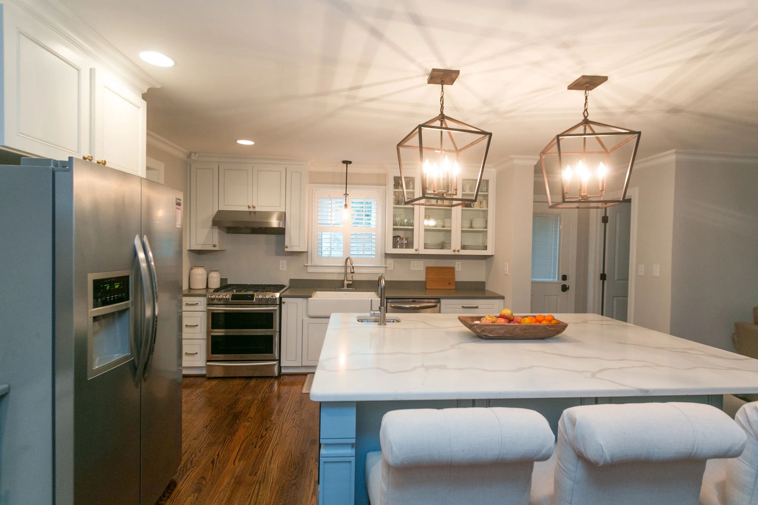 Gray quartz countertops on the perimeter of the kitchen cabinetry to highlight the veining in the Calcutta Vintage Quartz island top.