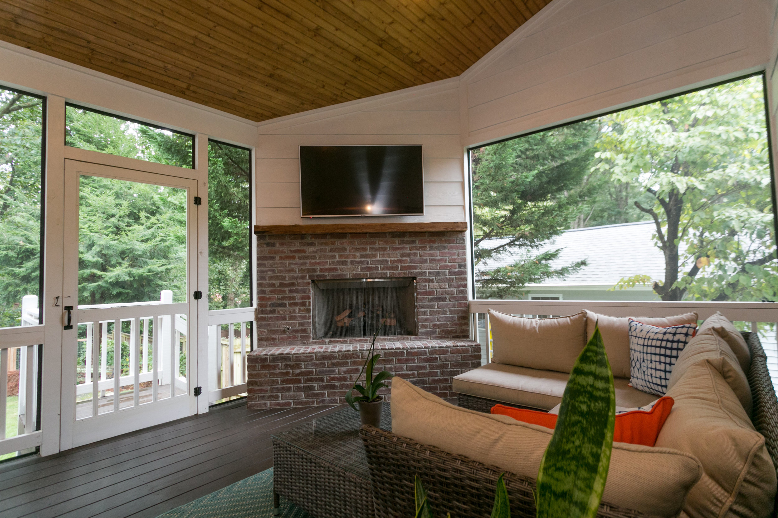 Outdoor Living Area: screened porch with stained tongue and groove ceiling, brick fireplace with reclaimed wood mantel. The oversized hearth adds additional seating.
