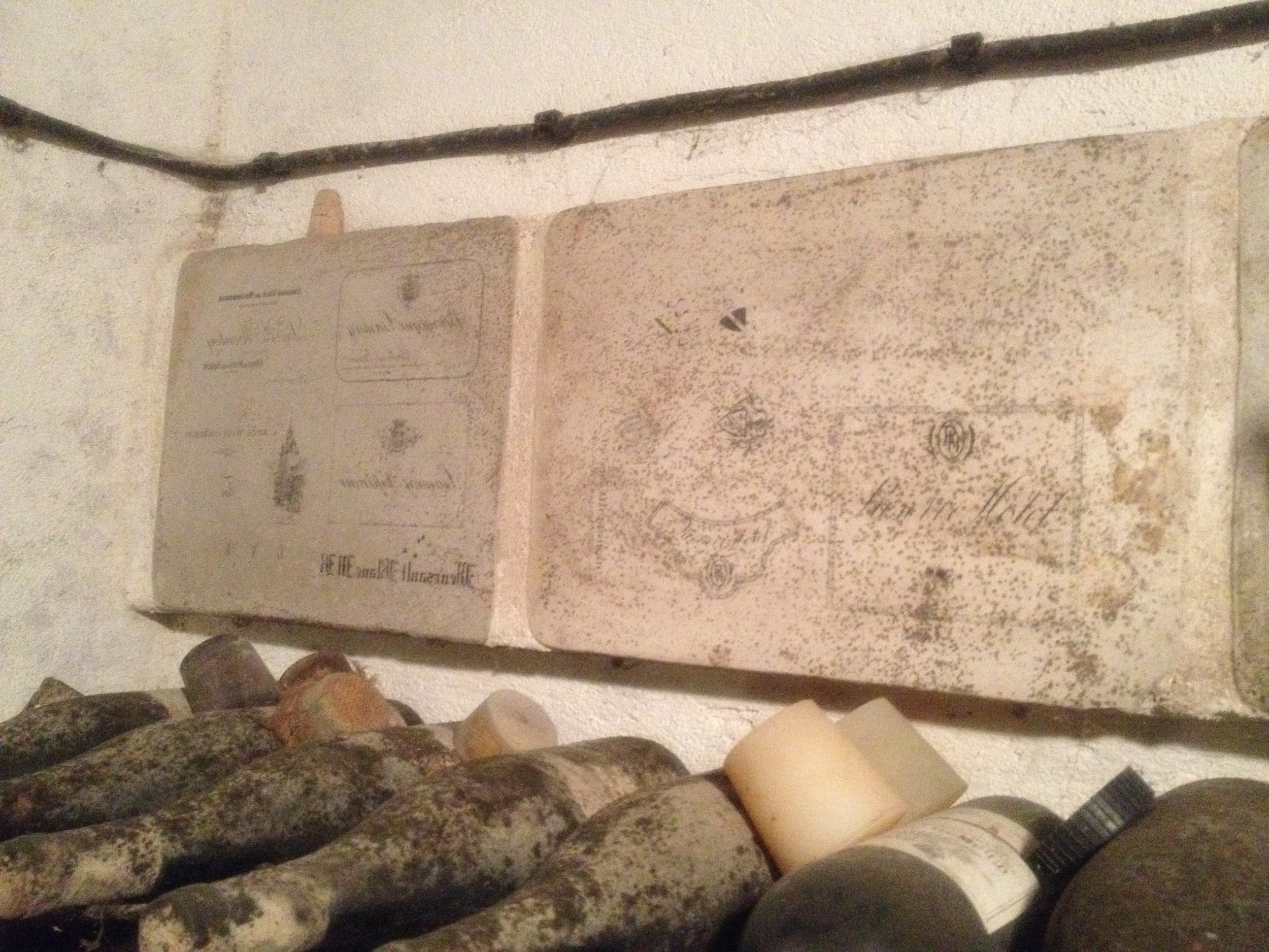 Cave Domaine Rossignol. Hanging above the aging bottles of wine are stone lithographs for hand printing labels.