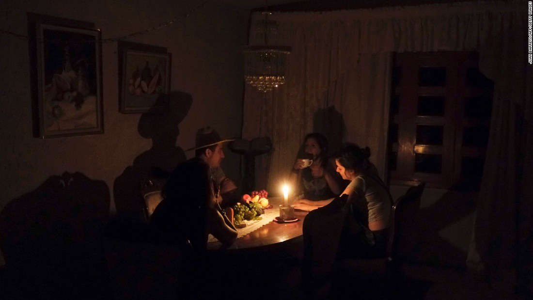 A family sit at a candle lit table in the state of Barinas, Venezuela. Food preparation, healthcare and survival is made difficult / Photo: cnn.com