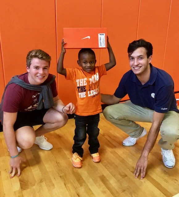 Kicks for Kids Gibson founders Nikolas Aixala and Connor Sazant with a young recipient.