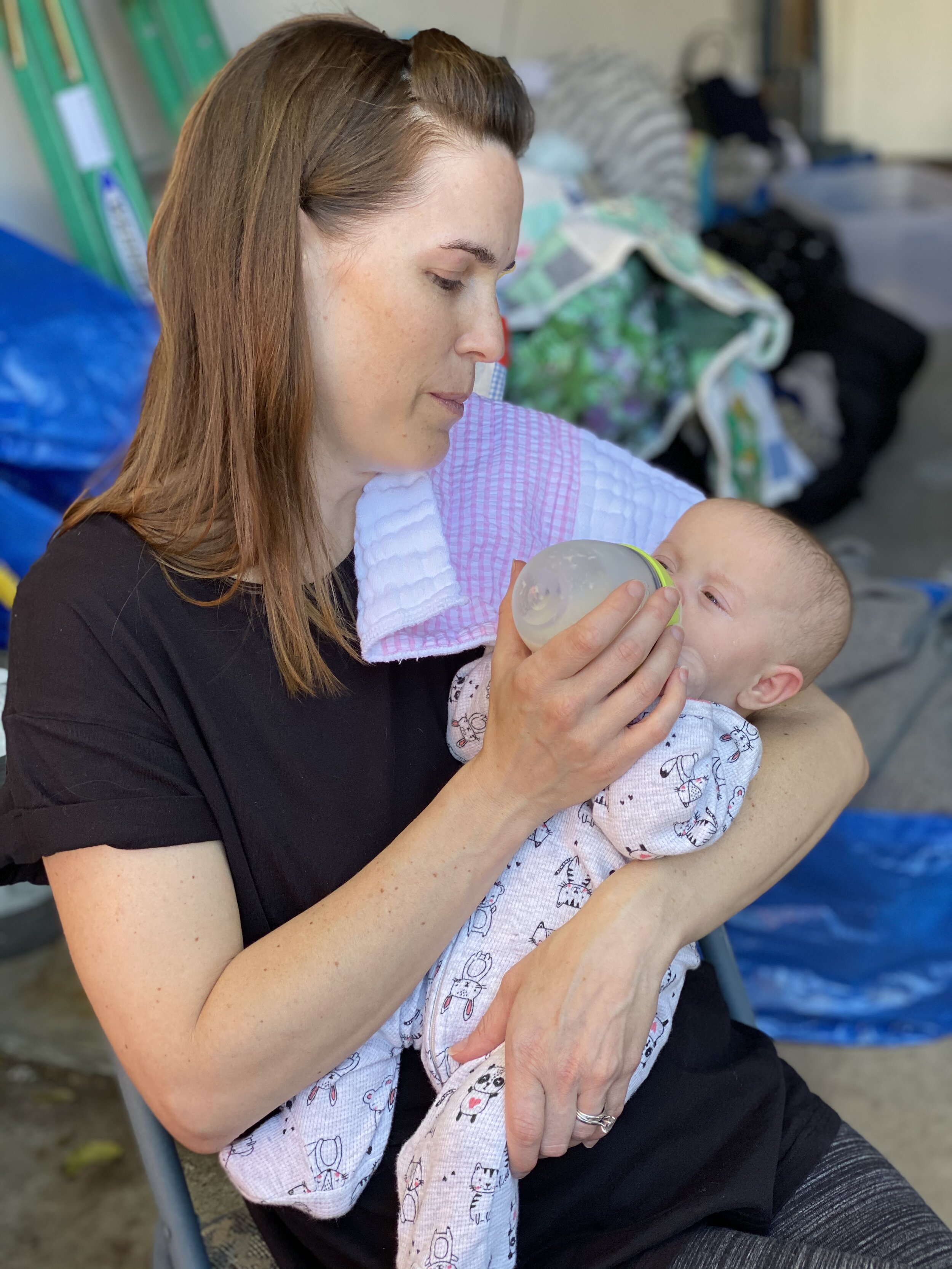  Elizabeth, still a mother to newborns in the midst of the recovery effort, takes a break from sorting through her things to feed a hungry Harper. 