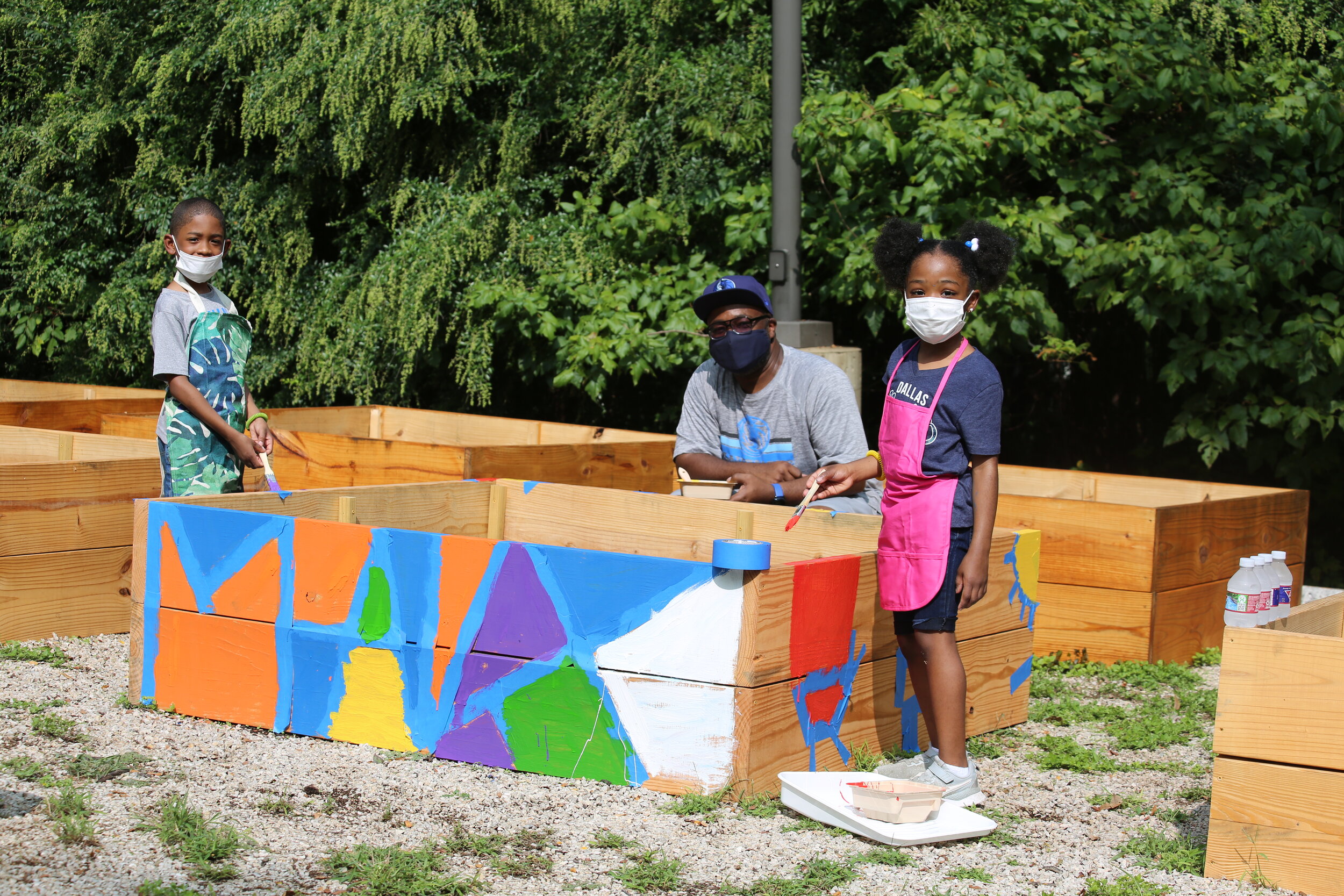 Nakia Douglas and his children painting garden boxes at The Mark Cuban Heroes Center.