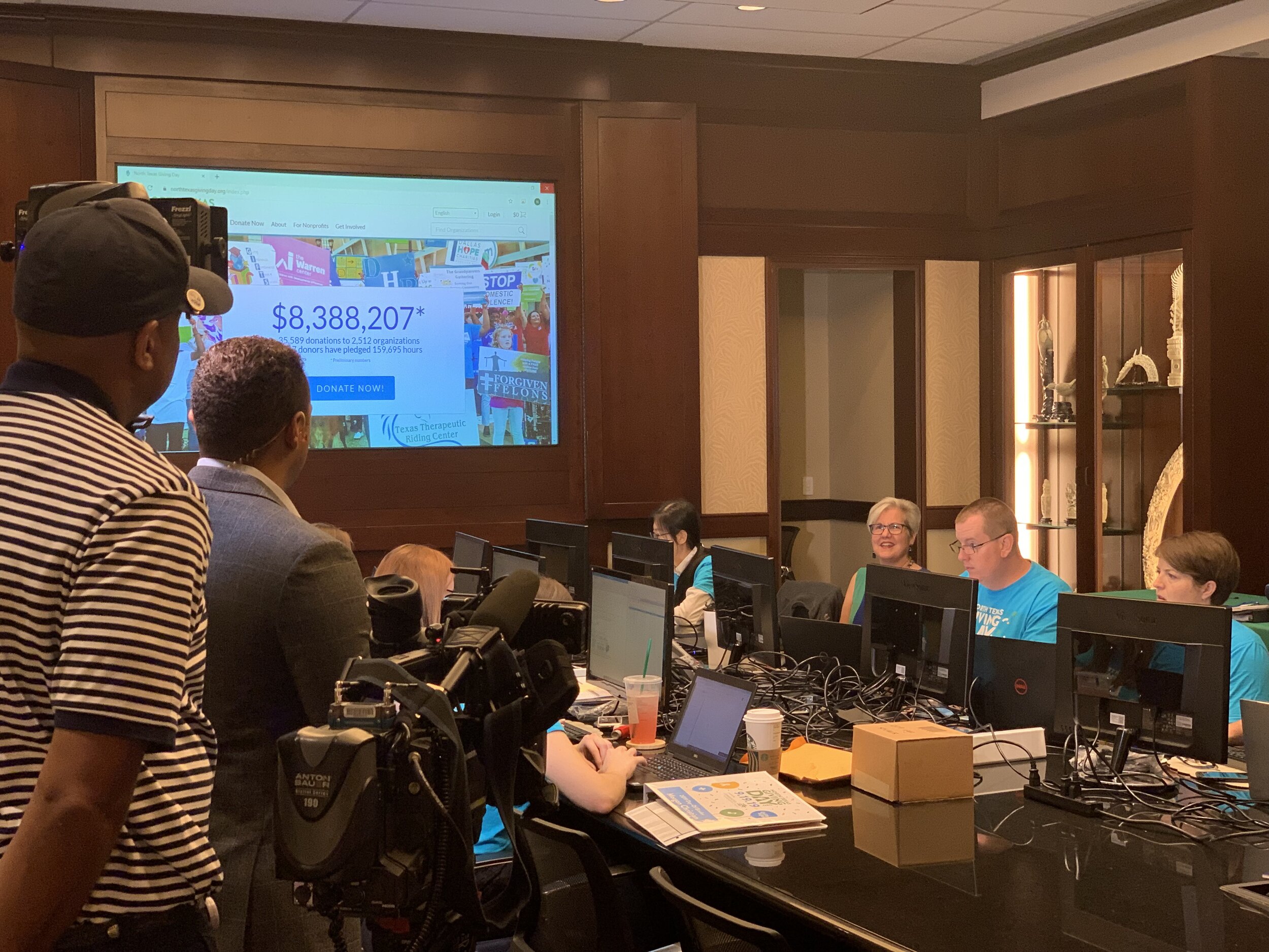 Behind the scenes in the 2019 NTxGD war room. SparkFarm invited TV cameras to capture the action as dawn broke and the day kicked off, monitoring website performance and sharing stats on a big screen. (Photo credit Carrie Dyer/SparkFarm.)