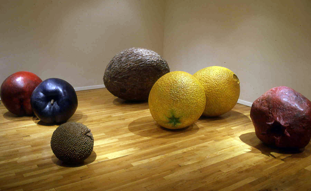 Ming Fay's 1990 Radiant Fruits sculptures in the Tirabia Gallery space. They're an assortment of giant hyper realistic sculptures of fruits laying on their sides on the floor. There's a lychee, a plum, a nectarine, a coconut, two lemons, and a pomegranate.