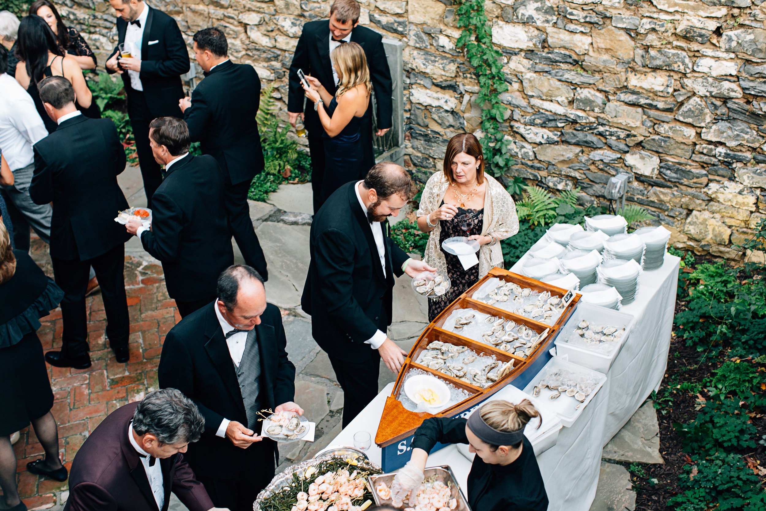 Guests serving themselves from a food station featuring a large realistic boat with oysters