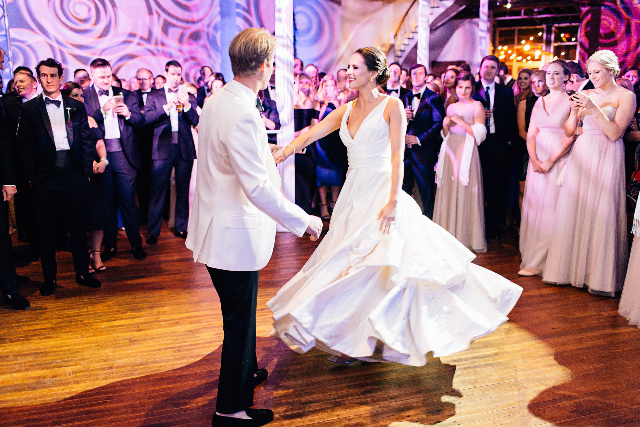 Groom twirling bride around colorful dance floor