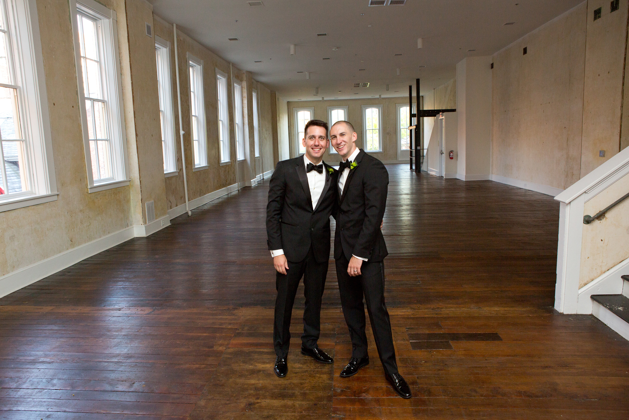 Groom &amp; Groom smiling for portrait in the Empire Room of Excelsior 